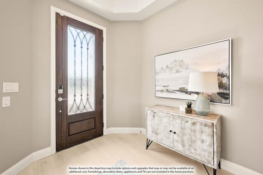 Home entryway with dark wood front door featuring decorative glass panel and console table with lamp on light hardwood floors