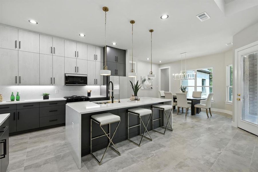 Kitchen with hanging light fixtures, a center island with sink, a kitchen breakfast bar, light stone countertops, and gray cabinets