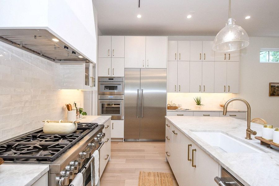Bright, modern kitchen featuring sleek white cabinetry, stainless steel appliances, and a large central island with marble countertops. Ample storage and counter space make it perfect for cooking and entertaining.