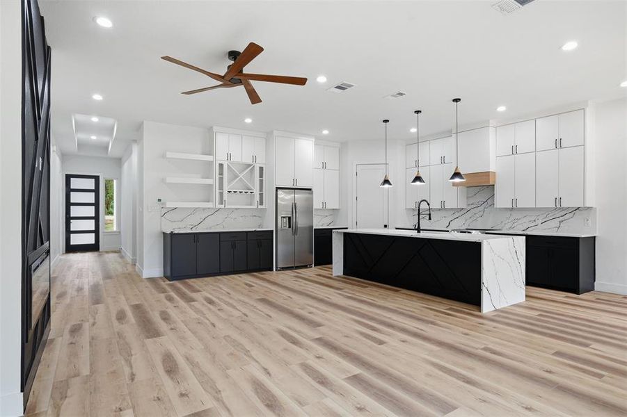 Open-concept living space featuring wood-finish flooring, a contemporary kitchen, and a dedicated beverage station