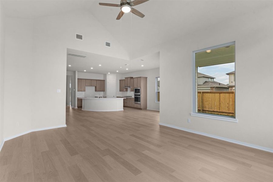 Unfurnished living room with high vaulted ceiling, light wood-style flooring, ceiling fan, and recessed lighting Unfurnished living room with high vaulted ceiling, light wood-style flooring, ceiling fan, and recessed lighting