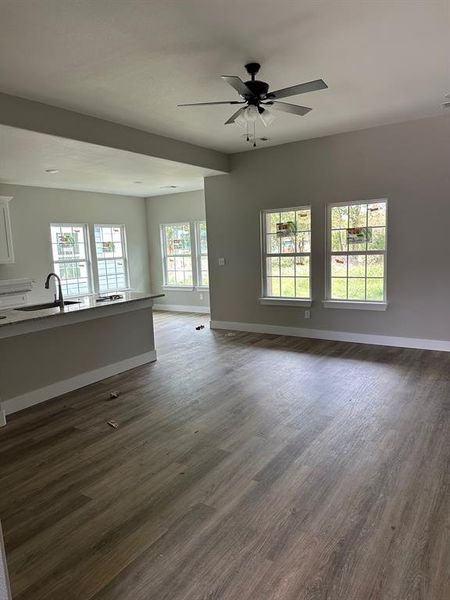 Unfurnished living room featuring plenty of natural light, dark wood-type flooring, and a ceiling fan Unfurnished living room featuring plenty of natural light, dark wood-type flooring, and a ceiling fan