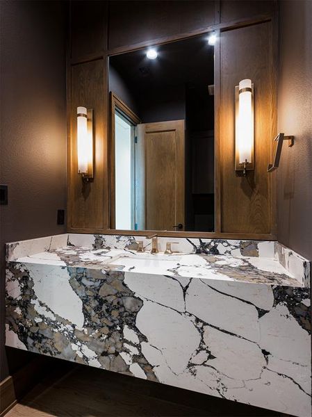 Designer powder bath near study with panel encased mirror and decorative lighting.