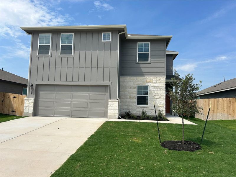 View of front of house featuring stone siding, a garage, board and batten siding, and driveway