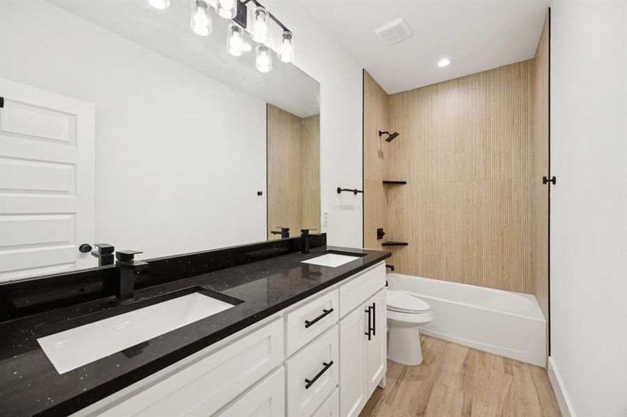Full bathroom with double vanity, light wood-type flooring,  shower combination, and recessed lighting