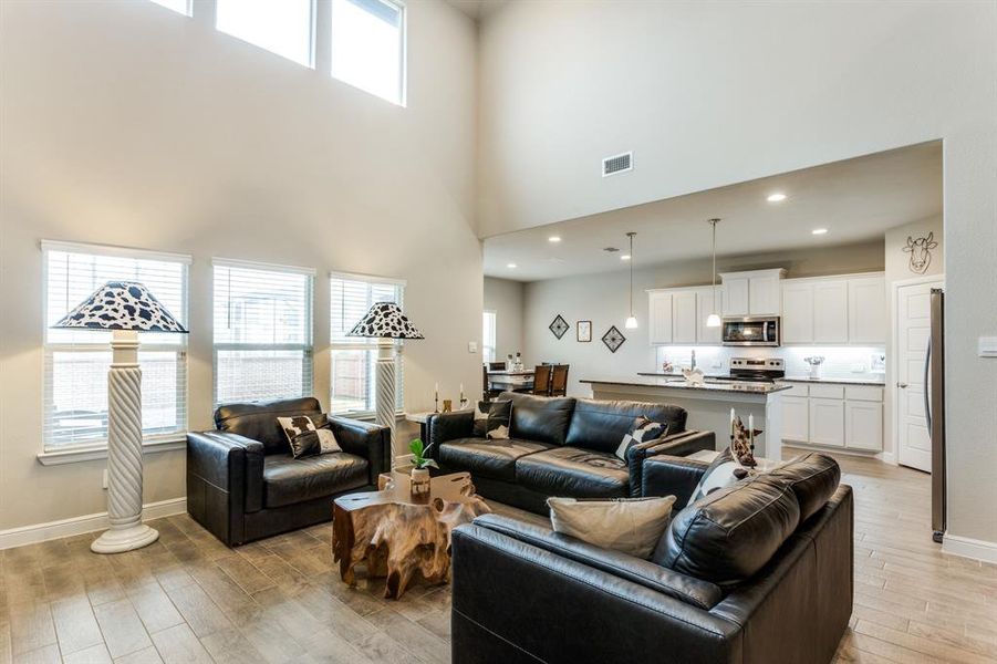 Living room with a high ceiling and light wood-type flooring