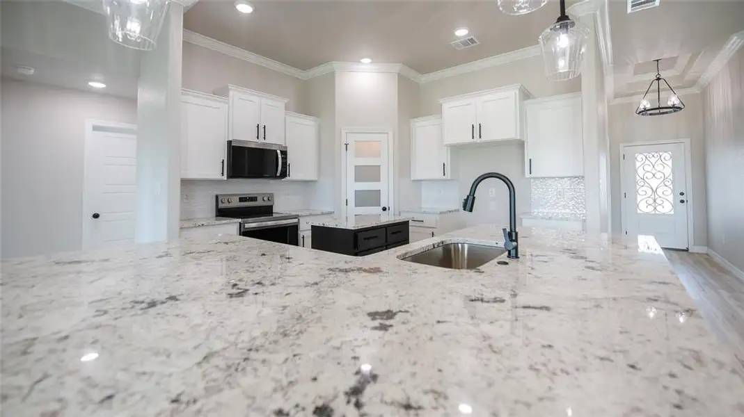 Kitchen featuring ornamental molding, tasteful backsplash, light stone counters, appliances with stainless steel finishes, and recessed lighting Kitchen featuring ornamental molding, tasteful backsplash, light stone counters, appliances with stainless steel finishes, and recessed lighting