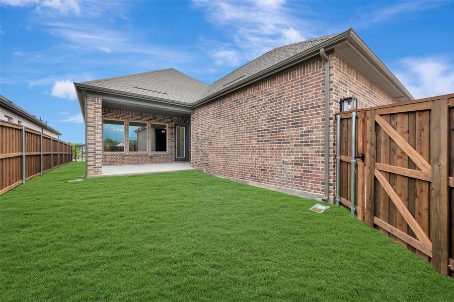 The property features a well-maintained lawn, a private wood fence, and an outdoor patio area