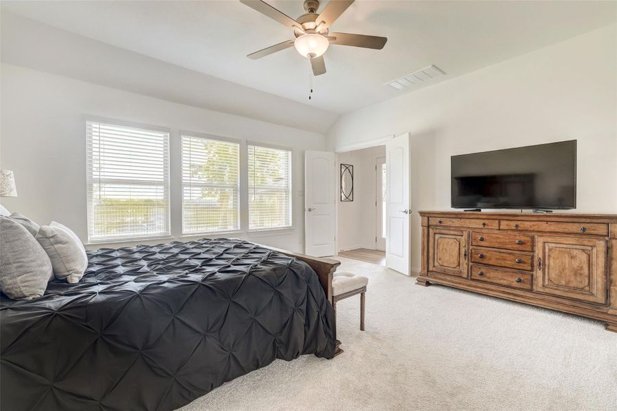 Bedroom with light colored carpet, vaulted ceiling, and a ceiling fan
