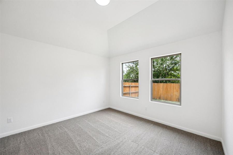 Carpeted empty room featuring baseboards and lofted ceiling Carpeted empty room featuring baseboards and lofted ceiling