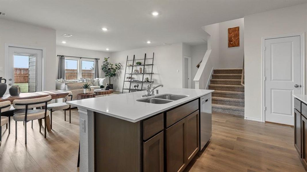 Kitchen featuring open floor plan, an island with sink, dark wood-type flooring, dark wood finish cabinets, and recessed lighting