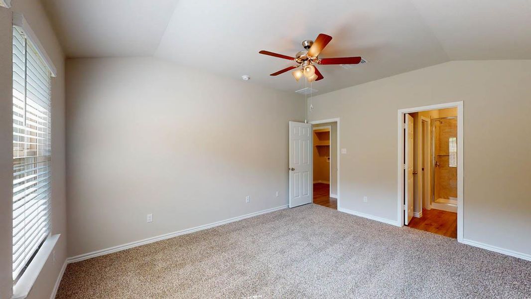 Unfurnished bedroom with lofted ceiling, carpet flooring, ceiling fan, and ensuite bath
