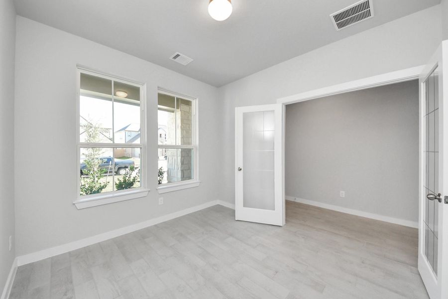 Experience the perfect blend of sophistication and warmth in this home office, boasting elegant wood-look tile flooring and flooded with natural light from expansive windows and French doors. Sample photo of completed home with similar floor plan. Actual colors and selections may vary.