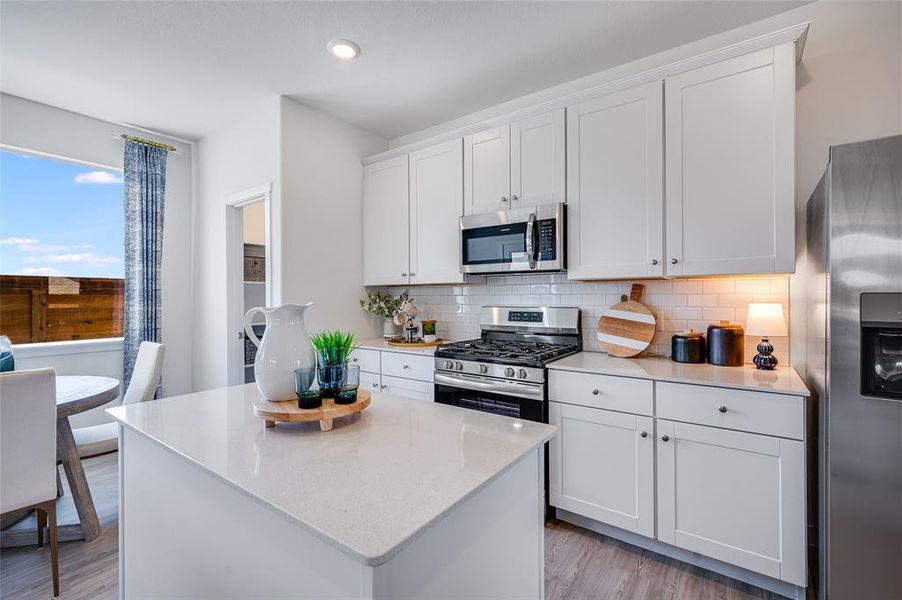 Kitchen featuring white cabinets, decorative backsplash, light hardwood / wood-style flooring, and appliances with stainless steel finishes