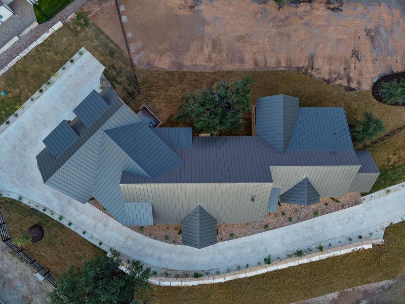 An aerial perspective reveals a modern residence with a distinctive multi-gabled roofline and an inviting curved driveway.