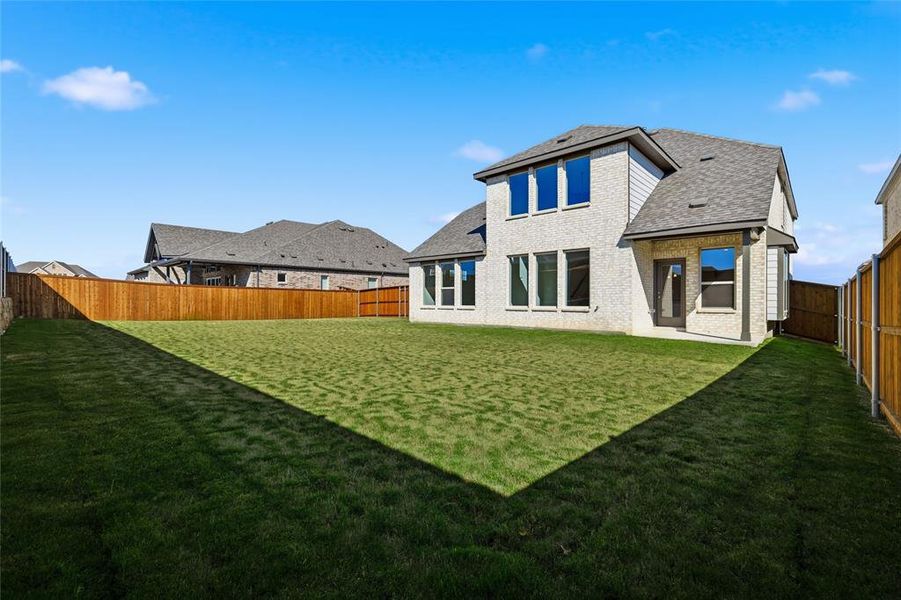 Rear view of property with a fenced backyard, a patio area, and a shingled roof