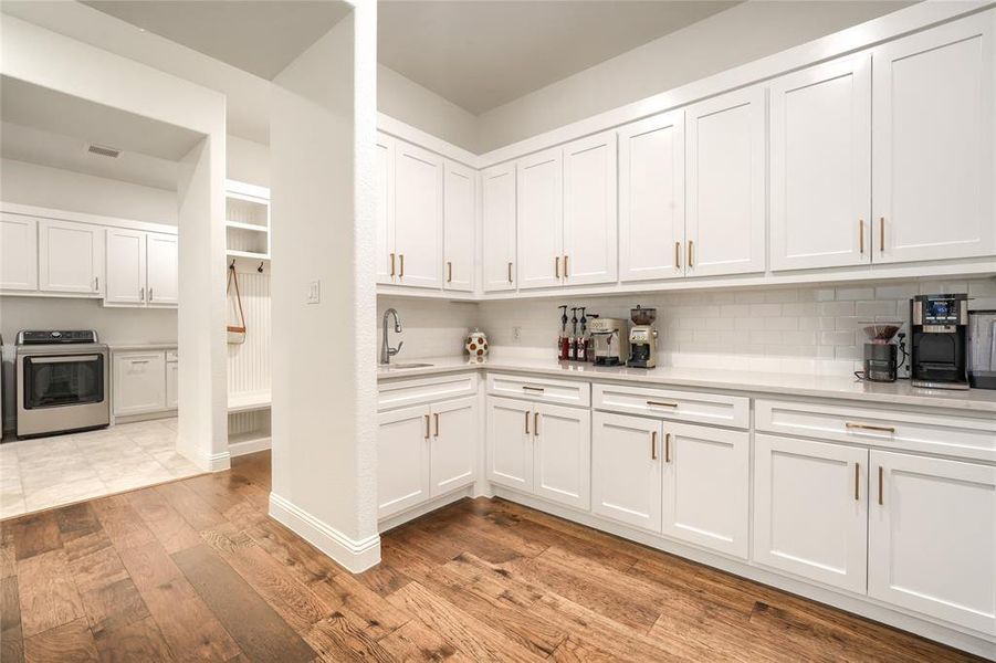 Kitchen with white cabinets, light wood-type flooring, stainless steel stove, and backsplash