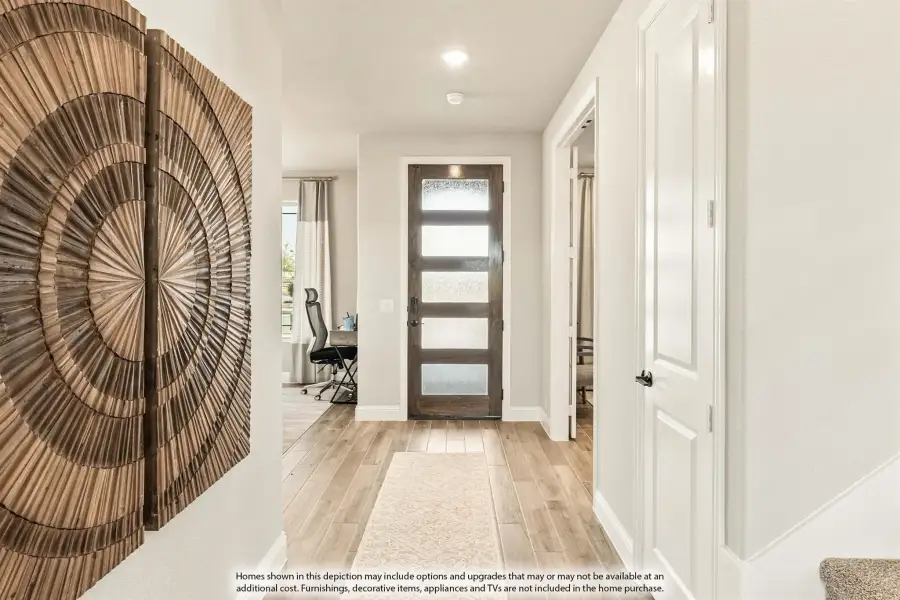 Entryway with dark wood front door with glass panels, light wood floors, and decorative wall art