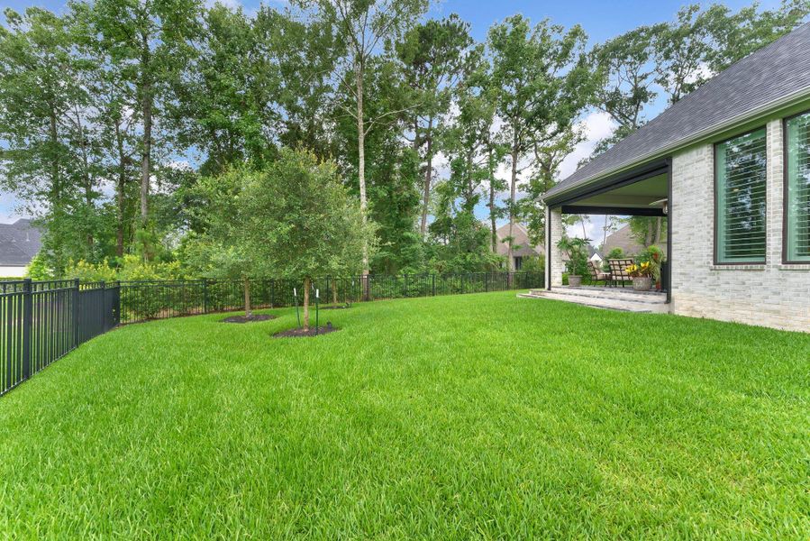 The side yard and backyard areas continue the home’s spacious, private feel with manicured lawn and mature natural surroundings. Three sides of openness help make the outdoor setting feel especially calm and expansive.
