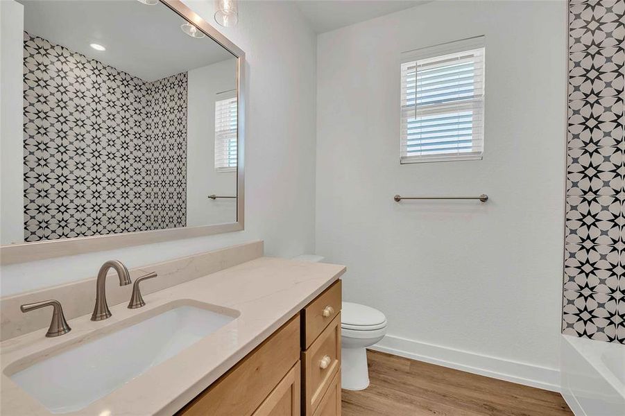 Bathroom with vanity, baseboards, toilet, and wood finished floors