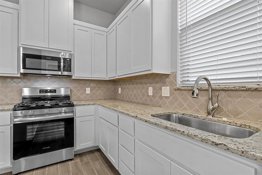 Kitchen with white cabinets, stainless steel appliances, and sink