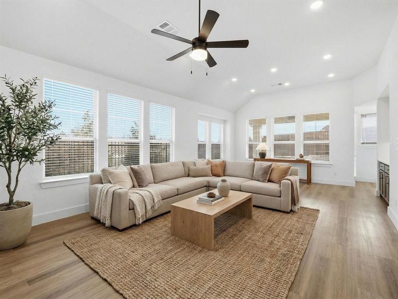 Virtually staged Living area featuring ceiling fan, light wood-style flooring, recessed lighting, healthy amount of natural light, and lofted ceiling