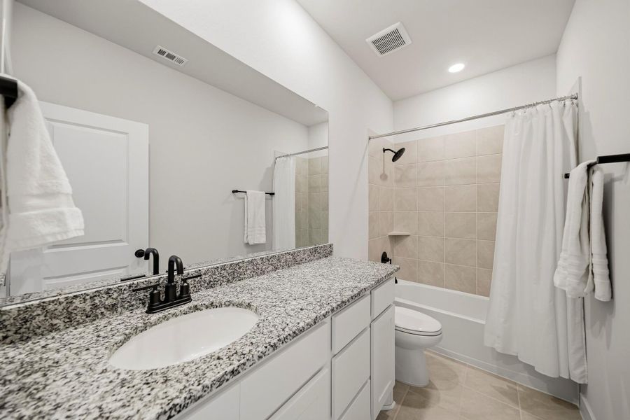 The fourth ensuite bathroom has tile flooring, a granite counter and recessed lighting, complemented by a combination tub/shower wrapped in an attractive tile surround for a clean, upscale finish. A closet sits opposite the sink.