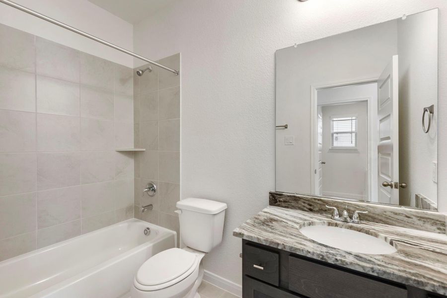 The secondary bathroom features a bath/shower combination, a sink with under-cabinet storage, and a neutral color palette.