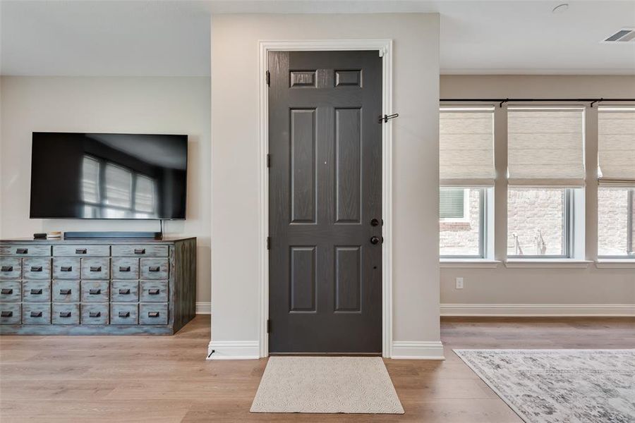 Entryway featuring a dark paneled door, upgraded Pergo water tight laminate wood look flooring, and white trim Entryway featuring a dark paneled door, upgraded Pergo water tight laminate wood look flooring, and white trim