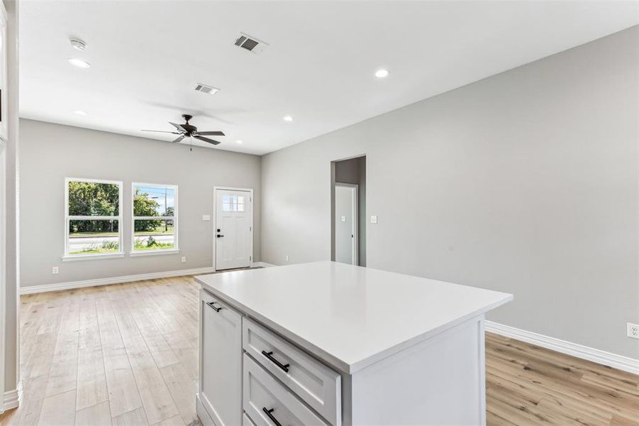 Kitchen featuring white cabinetry, light hardwood / wood-style flooring, a center island, and ceiling fan