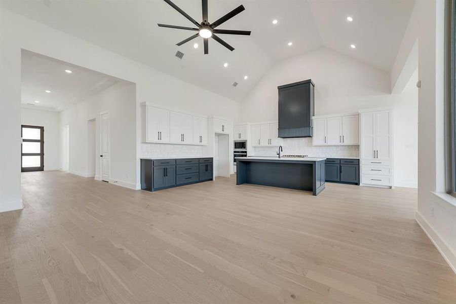 Unfurnished living room featuring high vaulted ceiling, light wood-style floors, recessed lighting, and ceiling fan Unfurnished living room featuring high vaulted ceiling, light wood-style floors, recessed lighting, and ceiling fan