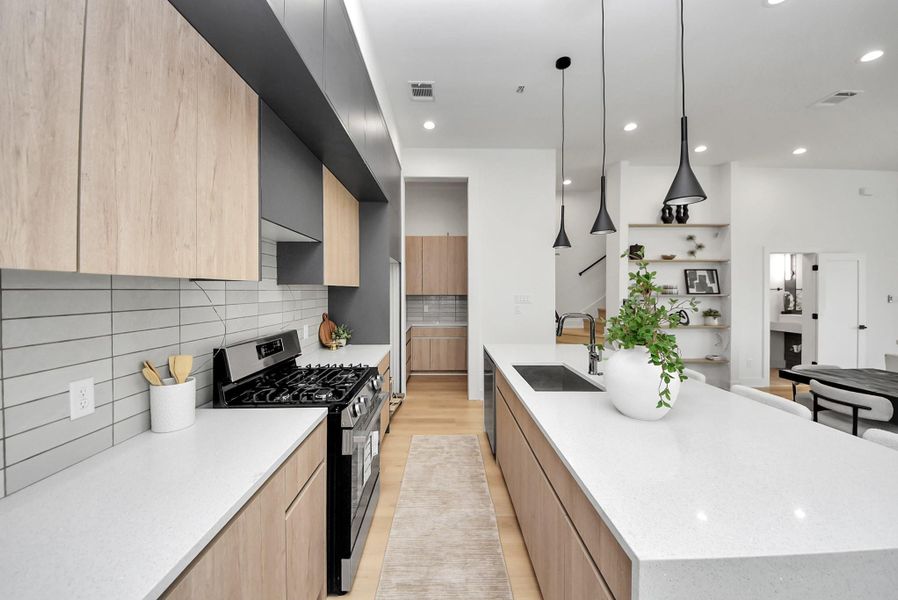 Chef-inspired kitchen featuring a gas range, large island with sink, pendant lighting, and walk-in pantry.