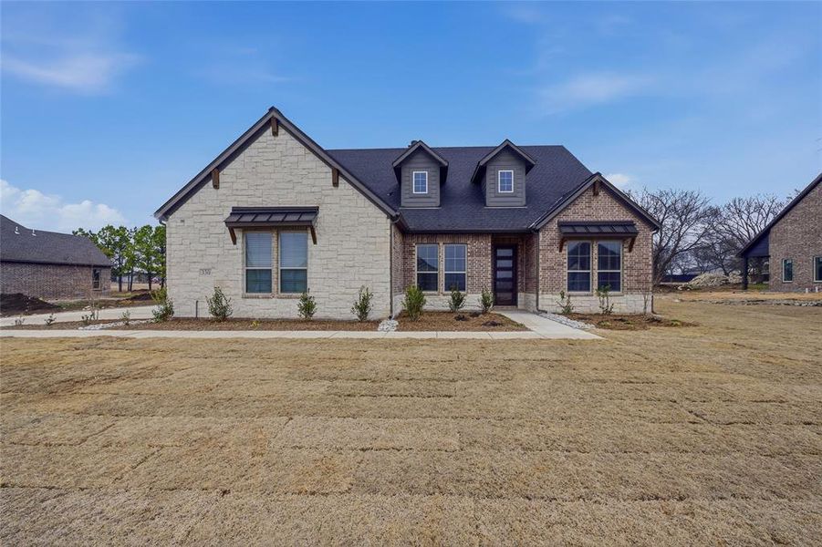 Craftsman inspired home with stone siding, a front yard, brick siding, and a shingled roof