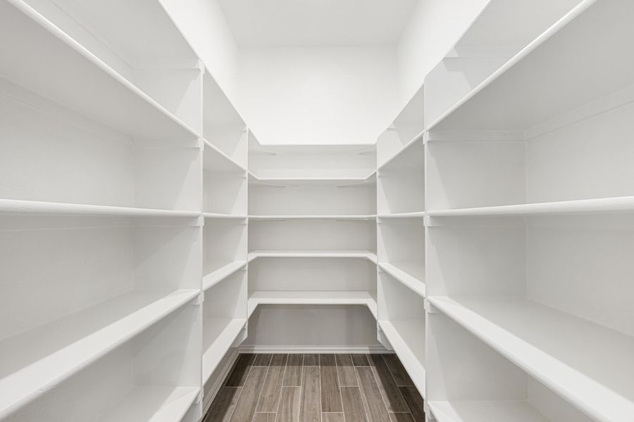 Walk-in pantry with white built-in shelves on three walls and wood-look tile floor Walk-in pantry with white built-in shelves on three walls and wood-look tile floor