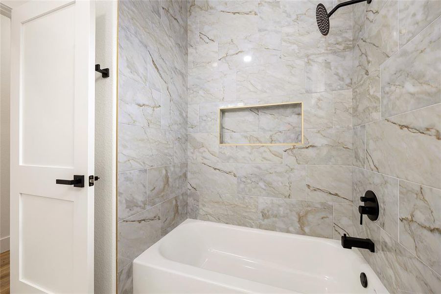 Elegant Secondary Bathroom with TubThis beautifully designed bathroom features a luxurious tub and shower combo with stunning marble-style tile, a built-in niche for convenience, and modern black fixtures. A perfect blend of elegance and functionality!