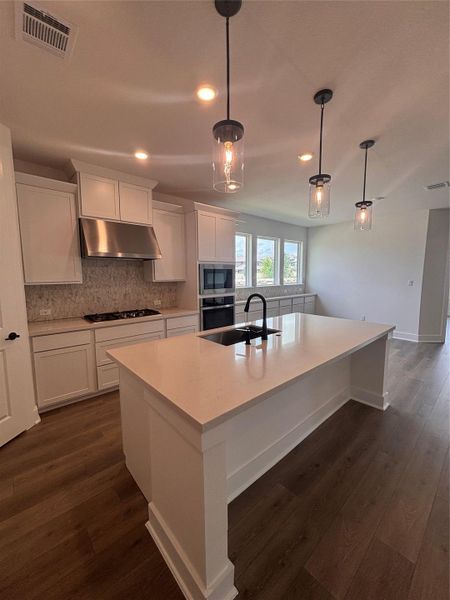 Kitchen with exhaust hood, a sink, cooktop, stainless steel oven, and recessed lighting Kitchen with exhaust hood, a sink, cooktop, stainless steel oven, and recessed lighting