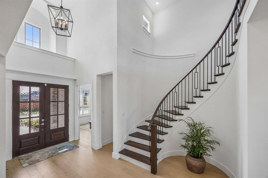 Foyer entrance featuring plenty of natural light, light wood finished floors, french doors, and a high ceiling