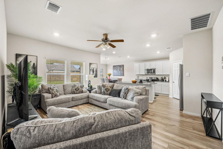 An open-concept living area flows into a contemporary kitchen, illuminated by recessed lighting.