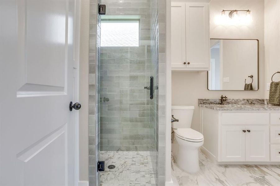 Modern bathroom featuring a glass-enclosed shower with subway tile surround and a tiled floor