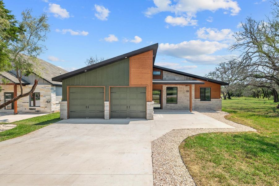 Contemporary home with a garage, concrete driveway, a porch, stone siding, and a front yard Contemporary home with a garage, concrete driveway, a porch, stone siding, and a front yard