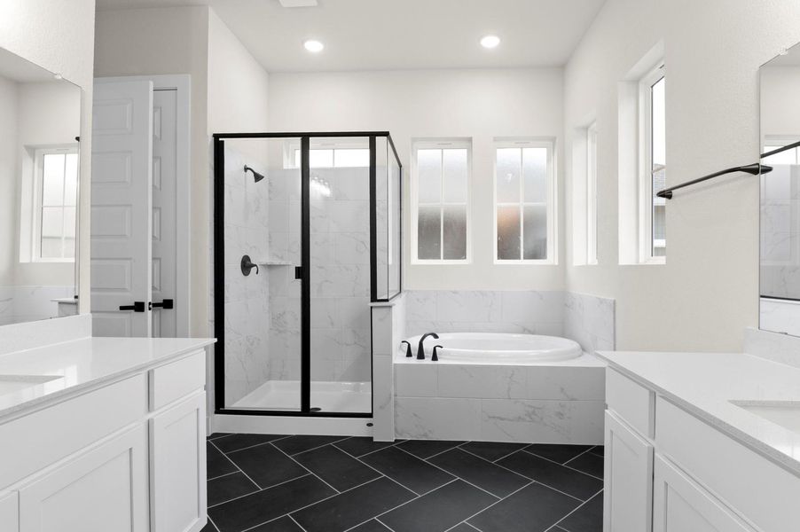 Bathroom with two vanities, a garden tub, a marble finish shower, recessed lighting, and dark tile patterned floors