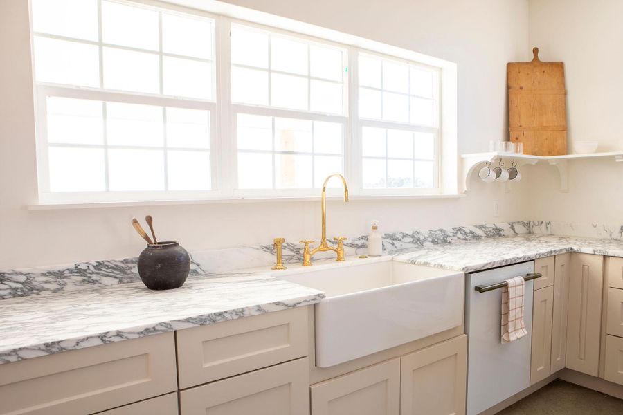 Kitchen with light stone countertops, cream cabinets, and dishwashing machine Kitchen with light stone countertops, cream cabinets, and dishwashing machine