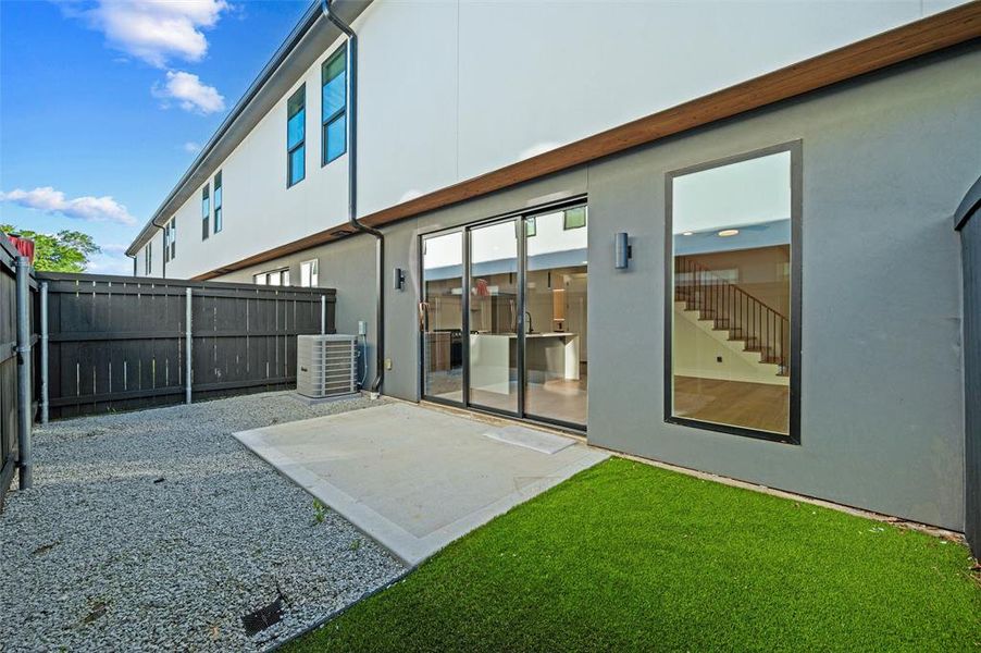 Backyard features a concrete patio overlooking the turf yard. Decorative gravel landscaping extends throughout the side yard. Large picture window and sliding glass doors provide views into the home. Wood privacy fencing encloses the outdoor space.