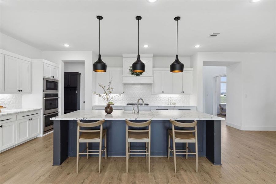 Kitchen featuring light wood-type flooring, a spacious island, and light stone counters