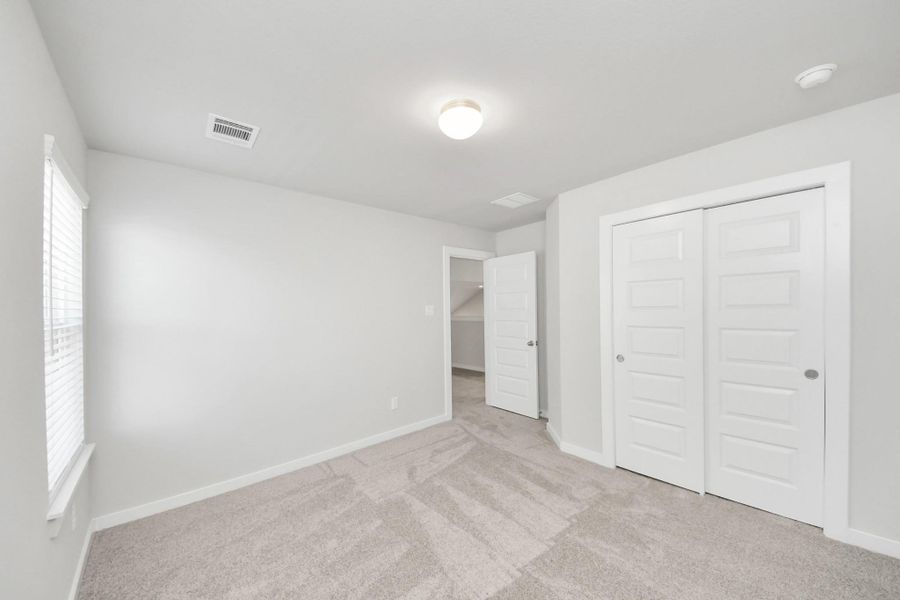 Generously sized secondary bedrooms featuring spacious closets, soft and inviting carpeting underfoot, large windows allowing plenty of natural light. Sample photo of completed home with similar plan. Actual colors and selections may vary. Call for more info.