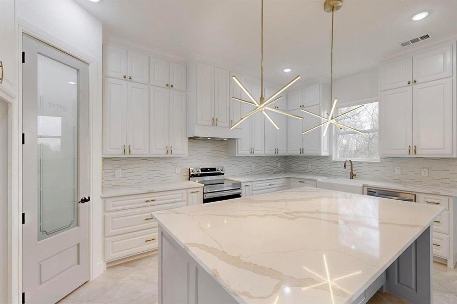 Kitchen featuring light stone counters, white cabinetry, and recessed lighting