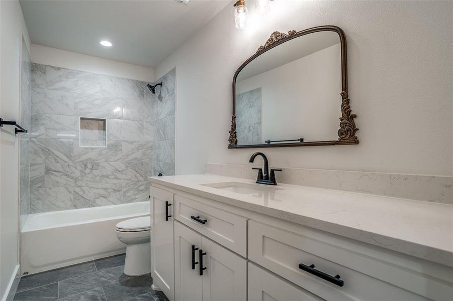 Full bathroom featuring vanity, toilet, and tiled shower / bath combo