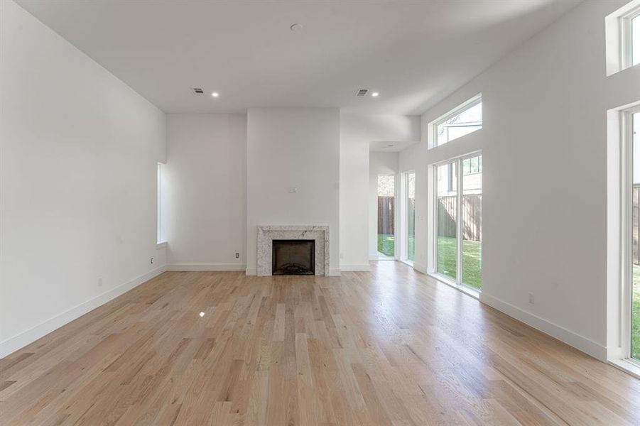 Unfurnished living room featuring a towering ceiling and light hardwood / wood-style flooring