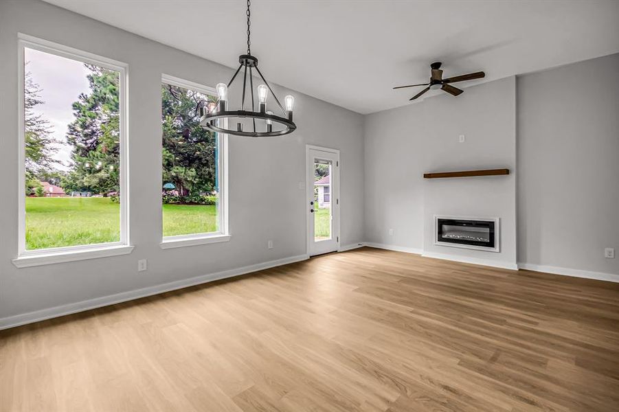 An electric fireplace with stained wood mantle provides a focal point. The large windows overlook the green belt behind the home.