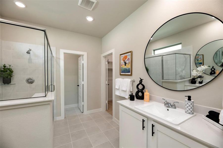 Full bathroom with a walk in closet, a stall shower, vanity, light tile patterned floors, and recessed lighting Full bathroom with a walk in closet, a stall shower, vanity, light tile patterned floors, and recessed lighting
